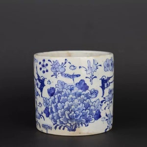 Peut inclure: Un cylindre en céramique blanche avec un motif floral bleu et blanc. Le motif présente des fleurs, des feuilles et des vignes stylisées.