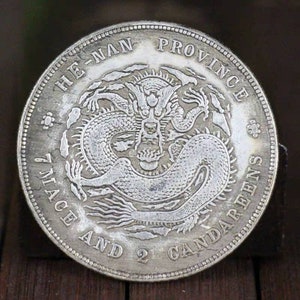 Pode incluir: Uma moeda chinesa de prata com um desenho de drag&atilde;o e a inscri&ccedil;&atilde;o "HE-NAN PROVINCE 7 MACE AND 2 CANDAREENS".