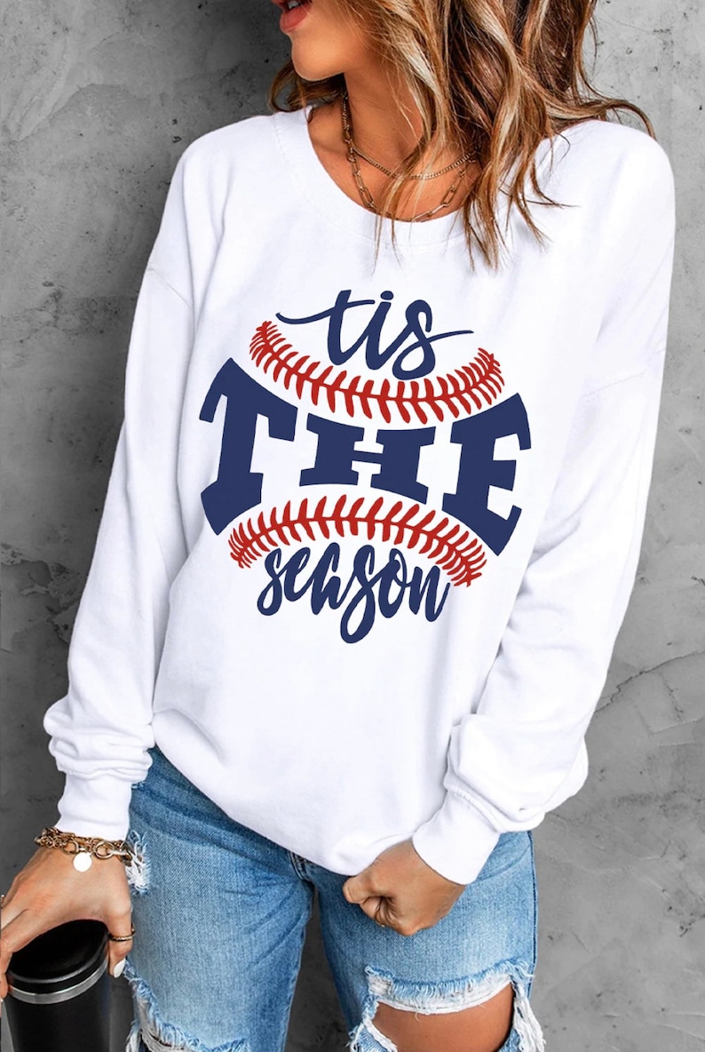 May include: White sweatshirt with a blue and red baseball graphic and the text "tis the season".