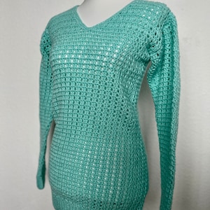 May include: A light green crochet sweater with a v-neck and long sleeves.