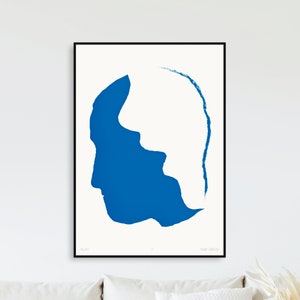 May include: A blue abstract silhouette of a person's head, with the right side of the head filled in with blue and the left side of the head left blank. The artwork is framed in a black frame and has the artist's name and title in the bottom corners.