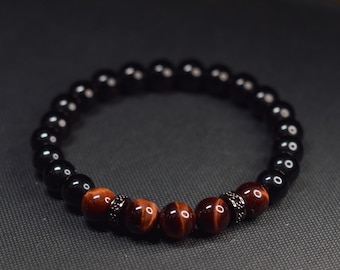May include: A black and brown beaded bracelet with silver accents. The bracelet is made with black onyx and tiger's eye beads.