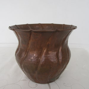 May include: A hammered copper planter with a fluted rim and a rounded, slightly flared body.