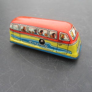 Puede incluir: Autobús de juguete vintage con techo rojo, carrocería amarilla y azul, y ventanas que muestran pasajeros. El autobús tiene la inscripción "Hungry Party". Un juguete coleccionable clásico.