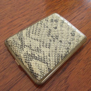 Peut inclure: Un étui à cigarettes vintage avec un motif de peau de serpent. L'étui est en métal et a une finition en laiton.