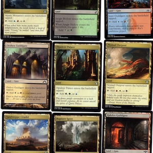 May include: A set of ten Magic: The Gathering cards featuring various lands and guildgates. The cards are in a gold and black frame with a white background. The cards feature different illustrations of landscapes and buildings.