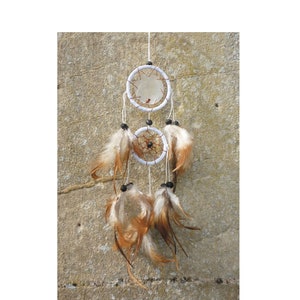 May include: A white dream catcher with two hoops and brown feathers hanging from the bottom. The dream catcher is hanging from a wall.