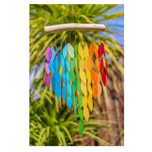 May include: A colorful wind chime with a wooden bar and hanging leaves in a rainbow of colors. The leaves are arranged in vertical rows, transitioning from purple to red. The chime hangs from a thin, natural-colored cord.