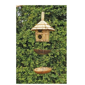 May include: A wooden bird feeder with a thatched roof and two feeding stations. The feeder is hanging from a tree branch and has a separate tray below for additional food.