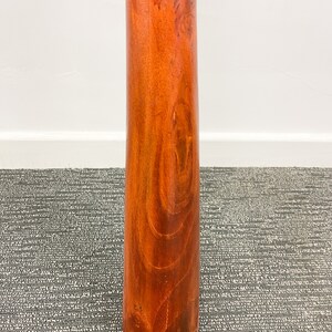 May include: A wooden didgeridoo with a colorful, patterned band around the top. The didgeridoo is brown and has a natural wood grain.