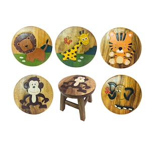 May include: Set of six wooden children's stools with animal designs. The stools feature a lion, giraffe, tiger, monkey, elephant, and another monkey. The stools are painted in bright colors and have a natural wood finish.