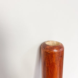 May include: Close-up of the top of a wooden didgeridoo, showing the smooth, reddish-brown wood and the open end of the instrument.