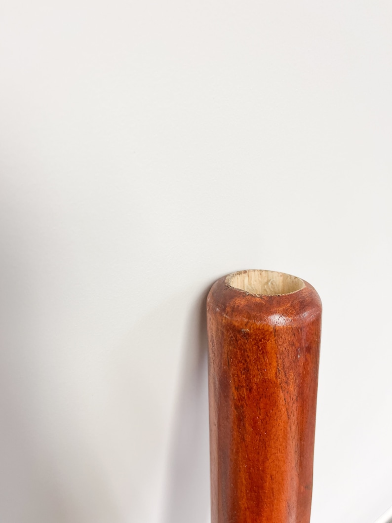 May include: Close-up of the top of a wooden didgeridoo, showing the smooth, reddish-brown wood and the open end of the instrument.