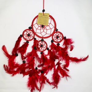 May include: Red dream catcher with four hoops and red feathers. The dream catcher has black beads and a tag that reads "Dream Catcher".