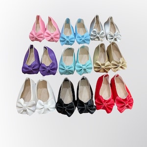 May include: Twelve pairs of doll shoes with bows in various colors, including pink, purple, blue, gold, white, black, and red.