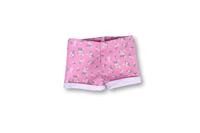 May include: Pink floral print shorts with a white cuff. The shorts have a small floral pattern.