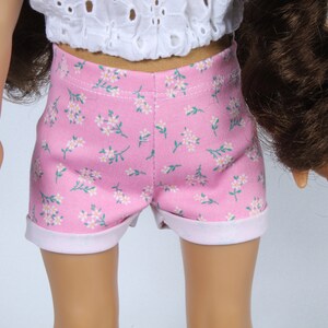 May include: Pink floral print doll shorts with a white trim. The shorts are made of a soft, lightweight fabric and have a comfortable fit.