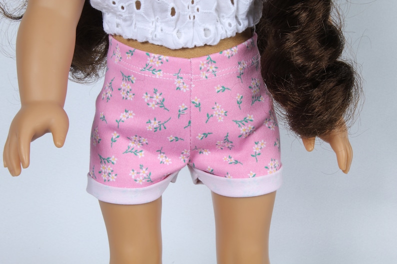 May include: Pink floral print doll shorts with a white trim. The shorts are made of a soft, lightweight fabric and have a comfortable fit.