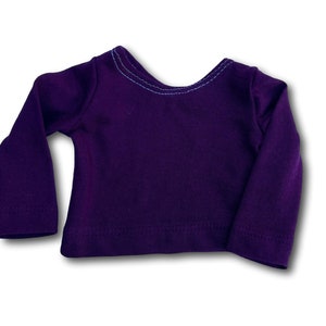 K&ouml;nnte beinhalten: Ein lang&auml;rmliges Hemd in tiefem Lila mit einem kontrastierenden blauen Stich um den Halsausschnitt.