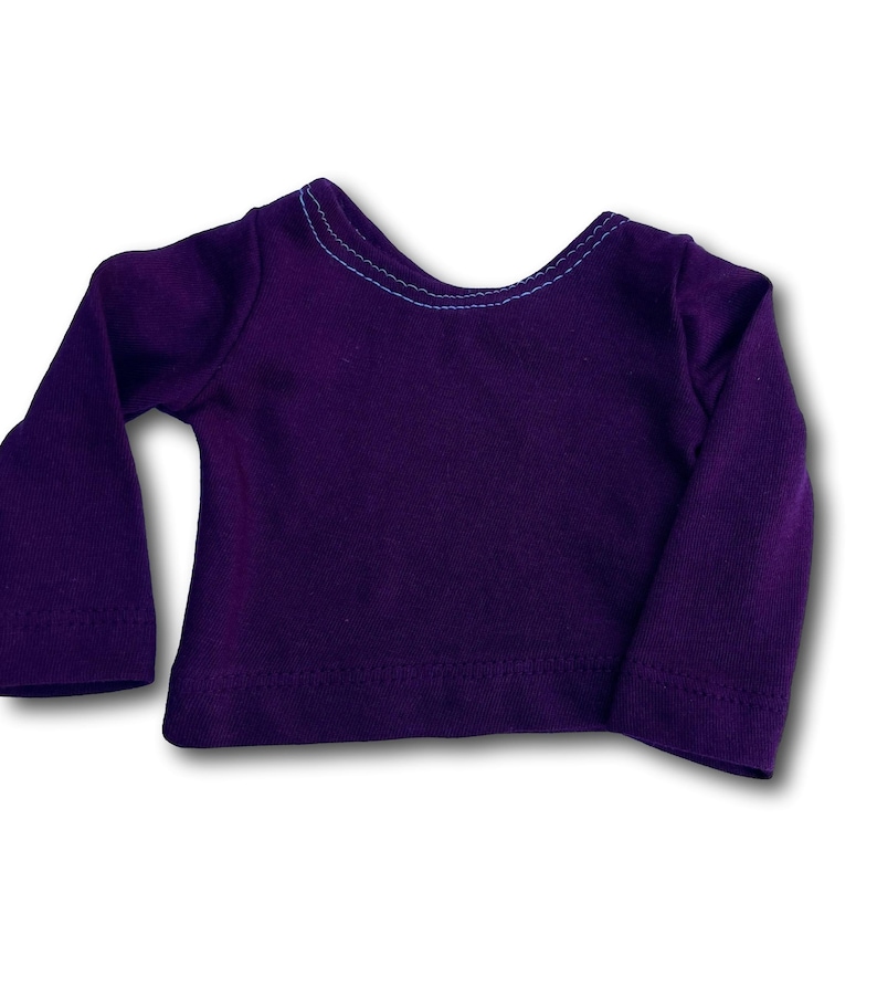K&ouml;nnte beinhalten: Ein lang&auml;rmliges Hemd in tiefem Lila mit einem kontrastierenden blauen Stich um den Halsausschnitt.