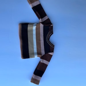 May include: A brown, black, and white striped long-sleeve shirt.
