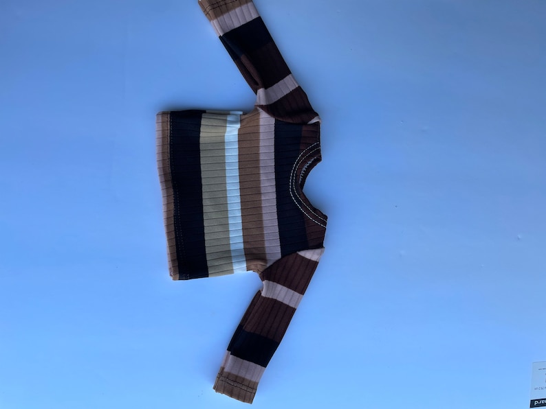 May include: A brown, black, and white striped long-sleeve shirt.