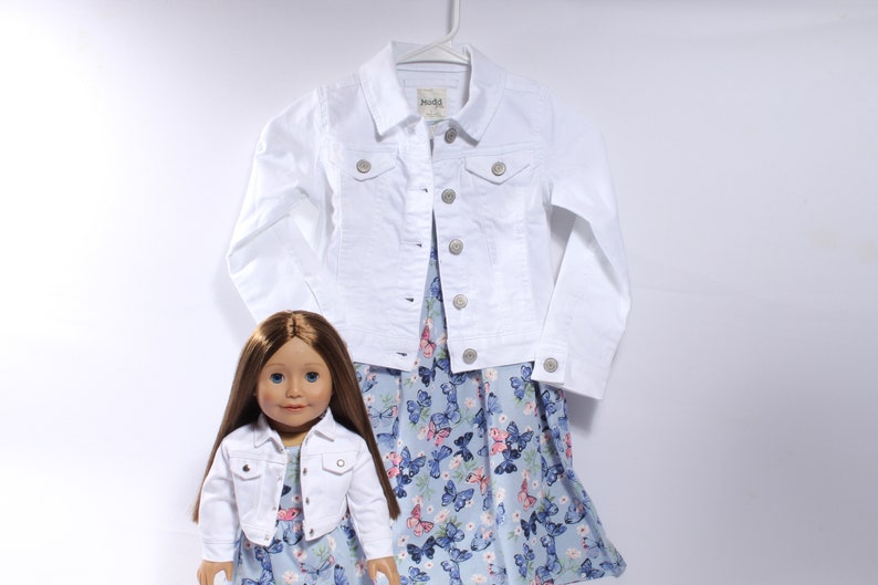 May include: A white denim jacket with a blue and white butterfly print dress. The jacket has a button closure and two pockets. The dress has a scoop neck and a flowy skirt.