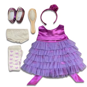 May include: A purple satin and tulle dress with a ruffled skirt, a white underskirt, white socks with pink hearts, a purple headband with a flower, a pair of purple shoes, and a wooden hairbrush.