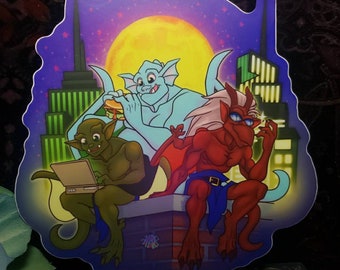 May include: A sticker featuring three cartoon gargoyles in a city setting. The gargoyles are green, blue, and red. The green gargoyle is using a laptop, the blue gargoyle is eating a sandwich, and the red gargoyle is holding a glass of wine. The sticker is set against a purple background with a yellow moon.