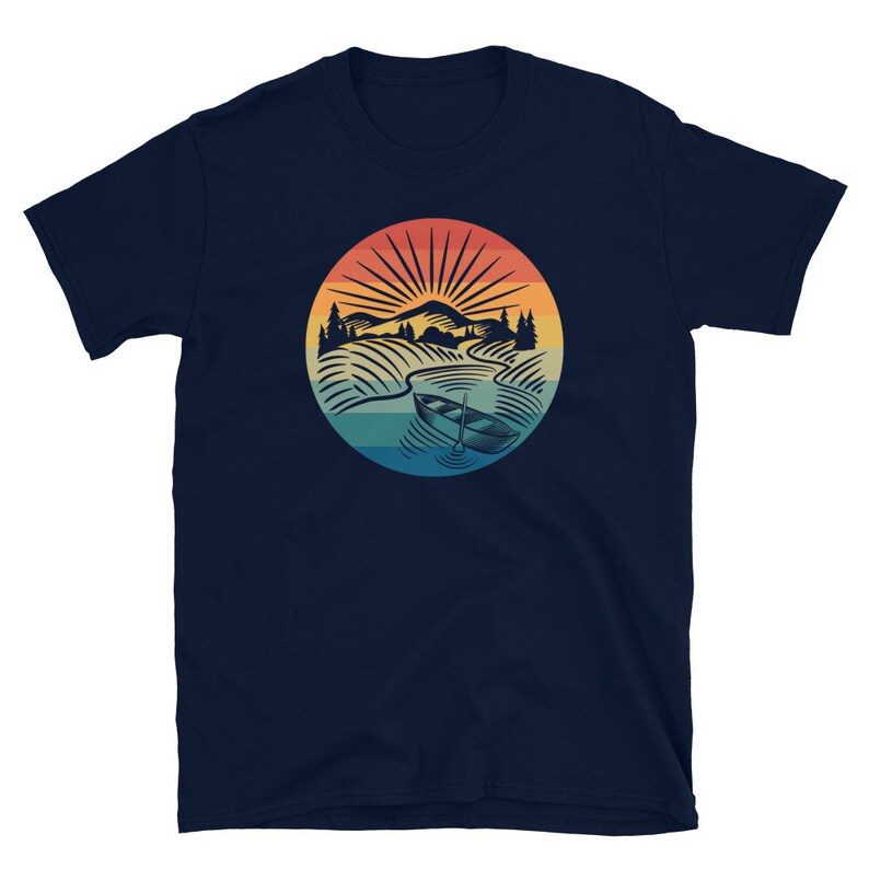 Pode incluir: Camiseta azul marinho com um gr&aacute;fico retro de um barco em um lago com montanhas e um p&ocirc;r do sol ao fundo.