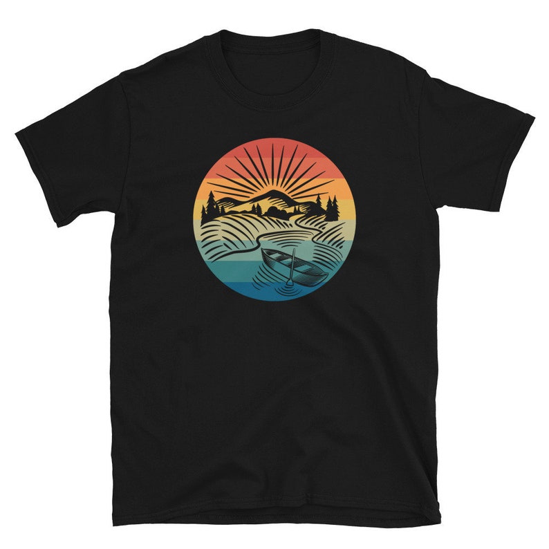 Pode incluir: Camiseta preta com um gr&aacute;fico retro de um barco em um lago com montanhas ao fundo. O gr&aacute;fico est&aacute; em tons de azul, amarelo, laranja e vermelho.