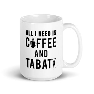 May include: White ceramic coffee mug with the text "ALL I NEED IS COFFEE AND TABATA" in black. The word "coffee" features a coffee cup icon. The mug has a curved handle.