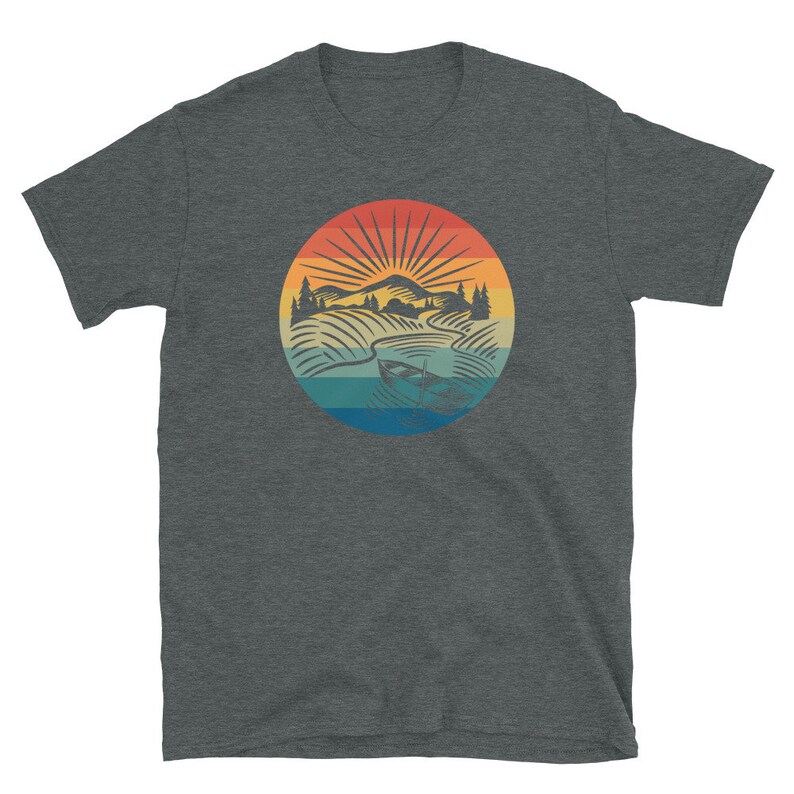 Pode incluir: Uma camiseta cinza escura mesclada com um gr&aacute;fico vintage de uma cena de lago com um barco. O gr&aacute;fico apresenta um p&ocirc;r do sol com cores laranja, amarelo e azul.