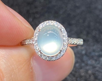 May include: A silver ring with a large oval-shaped moonstone set in a halo of small diamonds.