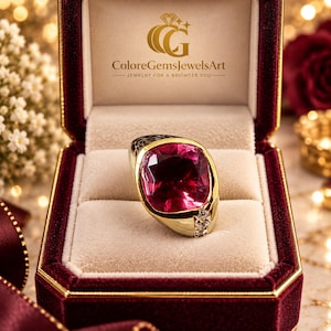 Peut inclure: Une bague en or ornée d'une grande pierre précieuse rose vif taille coussin, montée sur un anneau en or poli avec une incrustation noire texturée et une rangée verticale de trois petites pierres d'accent claires, dans un écrin en velours.