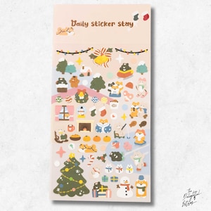 Può includere: Un foglio rettangolare di adesivi intitolato Daily sticker stay, che presenta varie illustrazioni a tema natalizio tra cui un albero di Natale, un pupazzo di neve, campane festive, calze, regali e piccoli animali in abiti invernali.