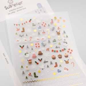 Può includere: Un foglio di adesivi Suatelier n. 106g Winter Love con varie piccole icone a tema natalizio tra cui pupazzi di neve, renne, muffole, cupcake, fiocchi di neve e accenti in lamina d'oro, con il testo Suatelier e Winter Love.