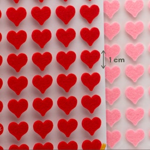 K&ouml;nnte beinhalten: Bl&auml;tter mit herzf&ouml;rmigen Filzaufklebern in Rot und Rosa. Die roten Herzen befinden sich links und die rosa Herzen rechts. Das Bild zeigt eine Messung von 1 cm. Die Aufkleber sind wahrscheinlich f&uuml;r Bastelarbeiten oder Dekorationen gedacht.