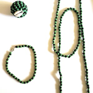 May include: A set of black and green beaded jewelry, including a necklace, bracelet, and a small beaded ball with a cowrie shell.