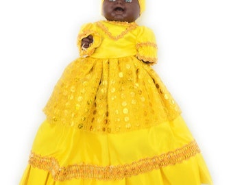May include: A yellow doll with a yellow dress and a yellow head wrap. The doll has black eyes and a black face.