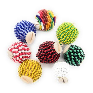 May include: Eight colorful beaded balls with a cowrie shell attached to each. The balls are made of small beads in various colors, including red, white, blue, green, yellow, and black.