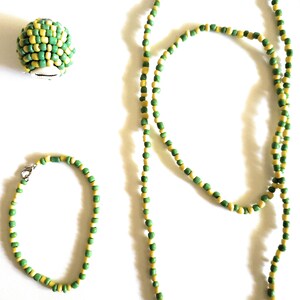 May include: A set of green and yellow beaded jewelry, including a necklace and a bracelet. The necklace is longer than the bracelet and both are made of small, round beads.