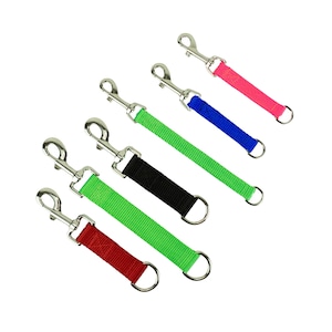 May include: Assortment of dog leash attachments in various colors, including red, green, black, blue, and pink. Each attachment features a metal clip and a D-ring, designed for easy attachment to a dog's collar or harness. The nylon straps are approximately 6 inches long.