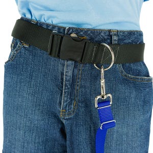 May include: A black nylon belt with a plastic buckle is fastened around blue denim jeans. A silver metal ring and clasp are attached to the belt, with a blue nylon strap hanging down. The belt is designed for pet owners.