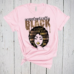 May include: Pink t-shirt with a black and gold graphic design. The graphic features a black woman's face with a gold afro and the words "unapologetically BLACK" in gold glitter letters. The words "beautiful, educated, pride, history, queen, dope, lady, smart, woman, magic, kind, loved" are also written in gold glitter letters around the woman's face.