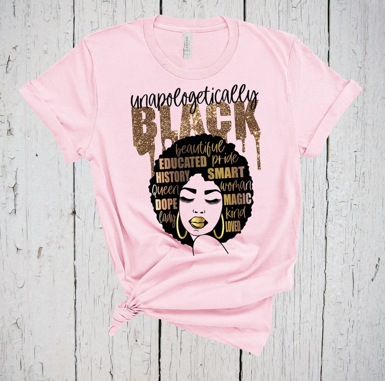 May include: Pink t-shirt with a black and gold graphic design. The graphic features a black woman's face with a gold afro and the words "unapologetically BLACK" in gold glitter letters. The words "beautiful, educated, pride, history, queen, dope, lady, smart, woman, magic, kind, loved" are also written in gold glitter letters around the woman's face.