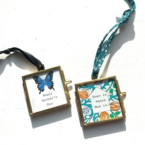 May include: Two small gold picture frames with a blue butterfly and the text "Happy Mother's Day" in one frame and a house with the text "Home is where Mum is." in the other frame.