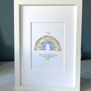 Könnte beinhalten: Ein weißer gerahmter Druck mit einem Regenbogen aus bunten Blumen. Der Text "Lyn" und "May you be proud of all you do, the person you are and the difference you make." ist unter dem Regenbogen gedruckt.