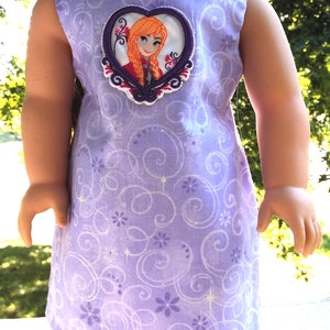 May include: Purple sleeveless dress with a white and purple swirl pattern. The dress has a heart-shaped applique featuring a cartoon image of a girl with red hair.