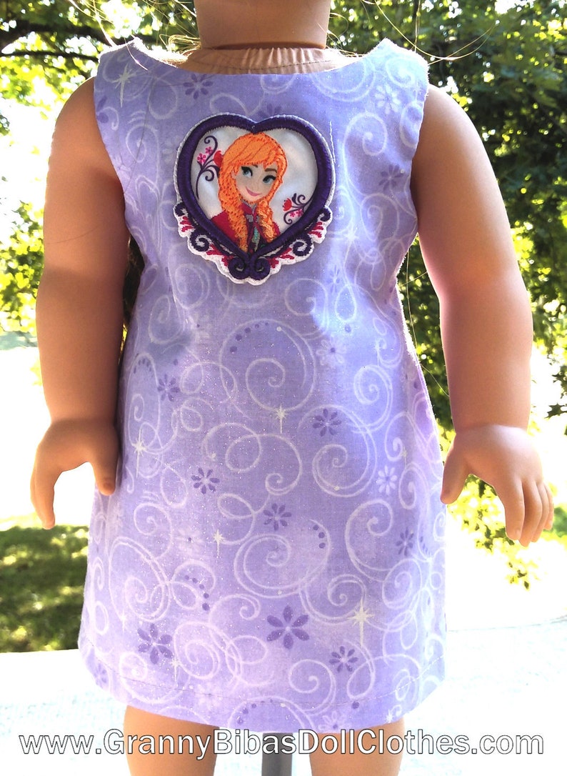 May include: Purple sleeveless dress with a white and purple swirl pattern. The dress has a heart-shaped applique featuring a cartoon image of a girl with red hair.